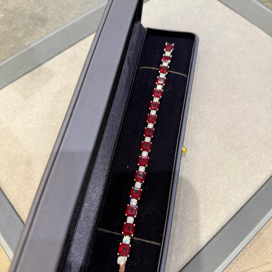 Jewelry box with a bracelet featuring red gemstones on a gray surface.