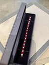 Jewelry box with a bracelet featuring red gemstones on a gray surface.