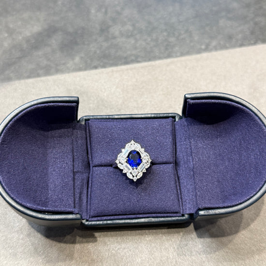 Blue velvet ring box with a diamond ring on a gray background