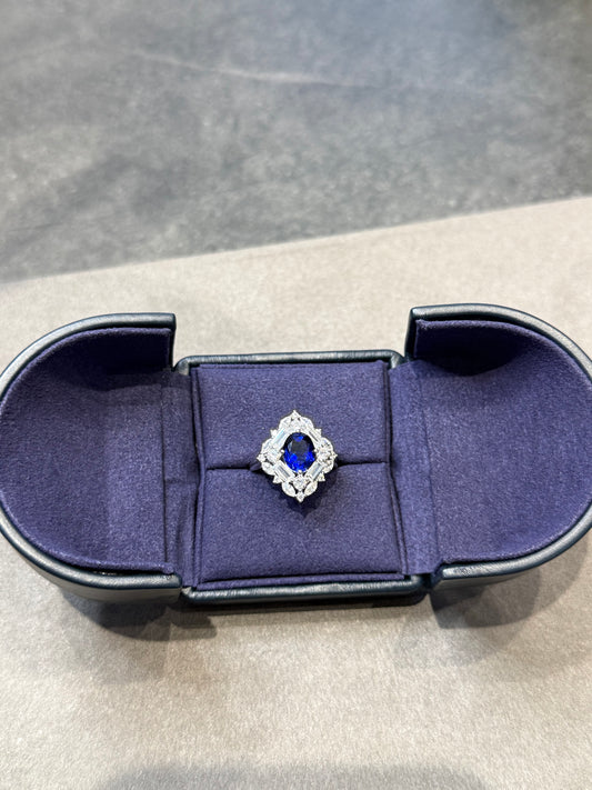 Blue velvet ring box with a diamond ring on a gray background
