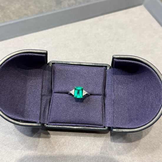 Emerald ring in a jewelry box on a light gray background
