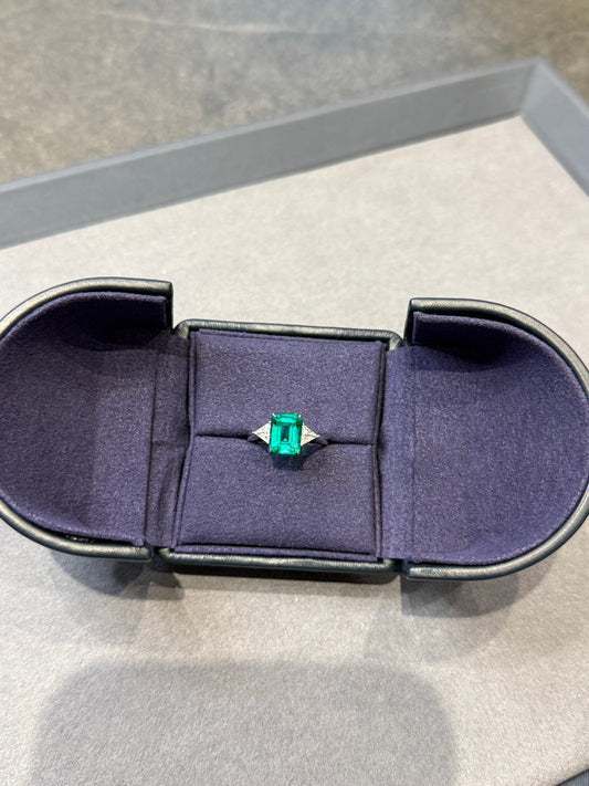 Emerald ring in a jewelry box on a light gray background