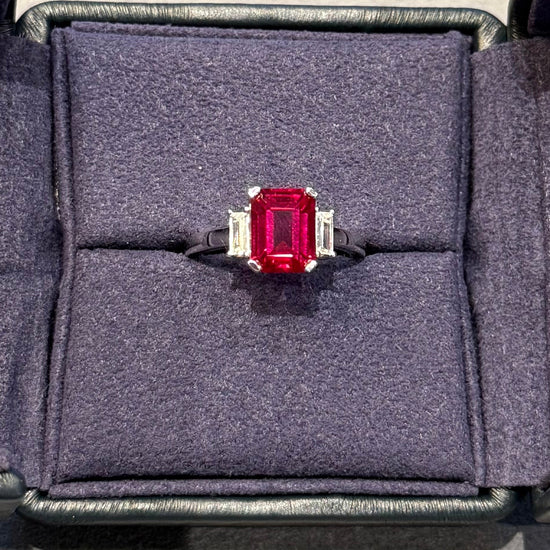 Ring with a red gemstone in a gray jewelry box on a light gray background