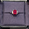 Ring with a red gemstone in a gray jewelry box on a light gray background