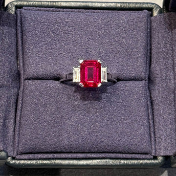 Ring with a red gemstone in a gray jewelry box on a light gray background