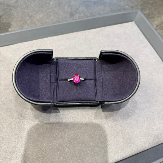 Ring with a pink gemstone in a black box on a gray surface