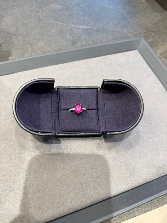 Ring with a pink gemstone in a black box on a gray surface
