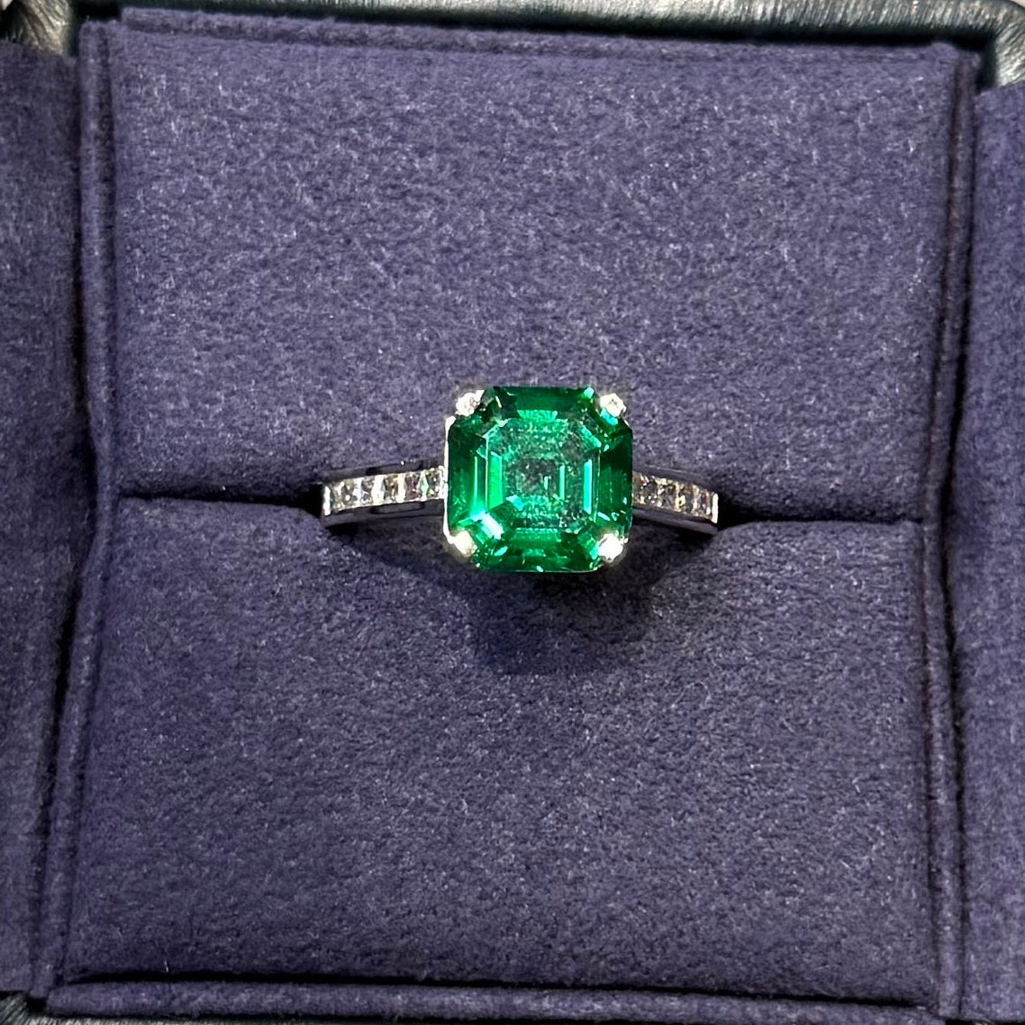 Ring with a green gemstone in a purple box on a gray surface