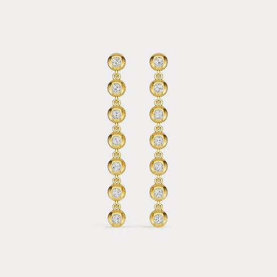 Gold earrings with clear stones on a light gray background
