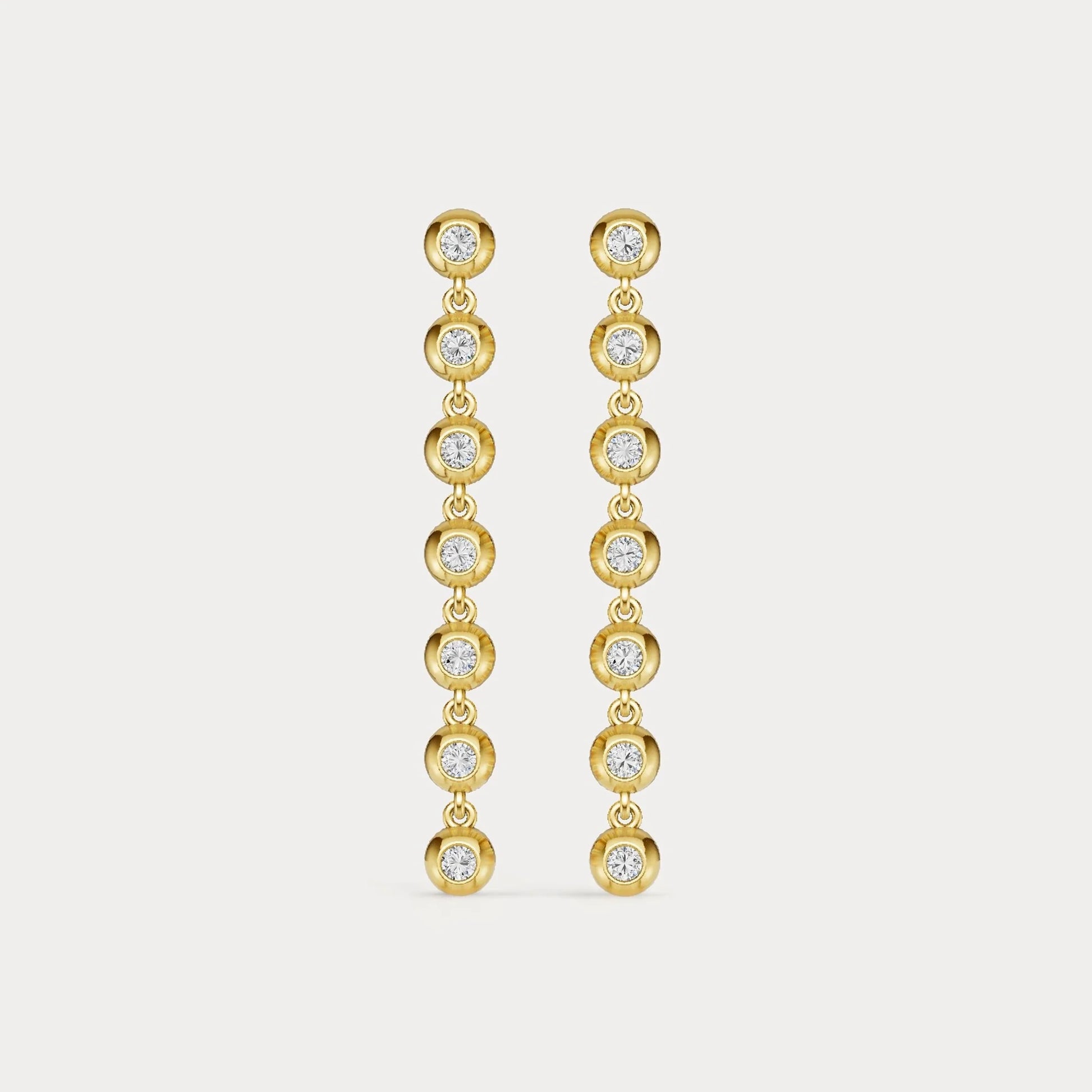 Gold earrings with clear stones on a light gray background