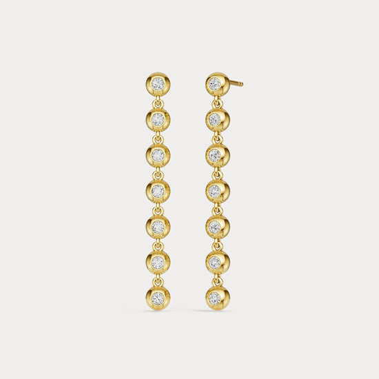 Gold earrings with clear stones on a light gray background