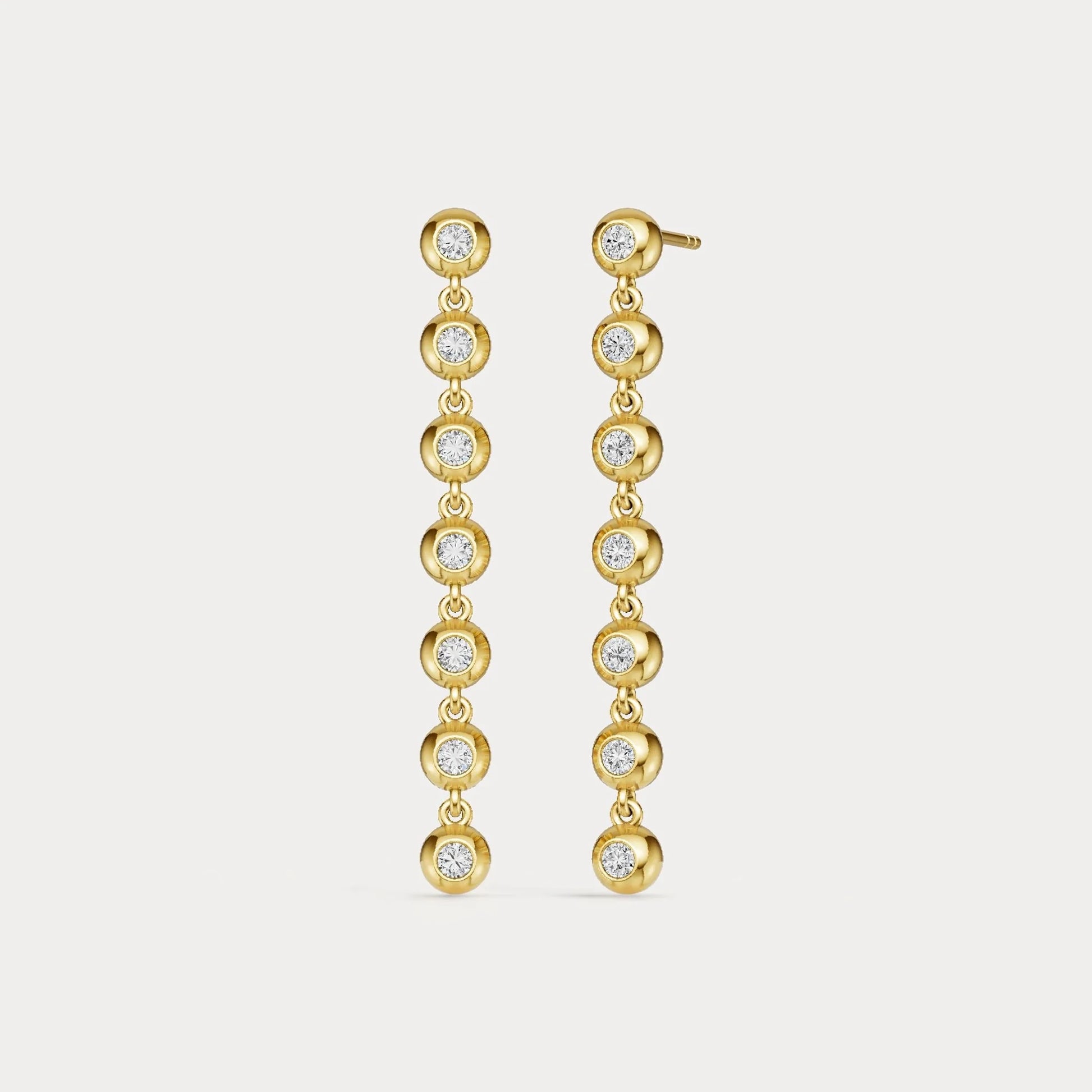 Gold earrings with clear stones on a light gray background
