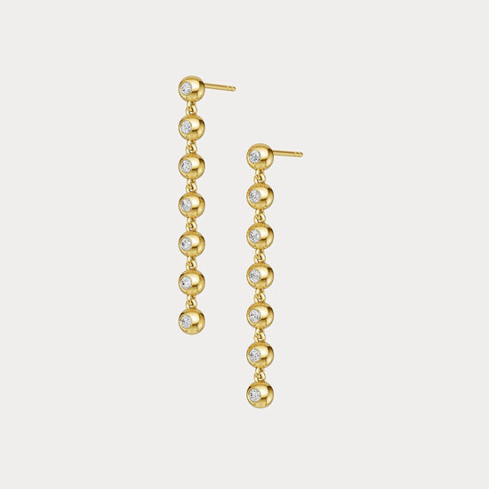 Gold earrings with embedded diamonds on a light gray background