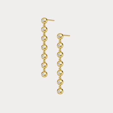 Gold earrings with embedded diamonds on a light gray background