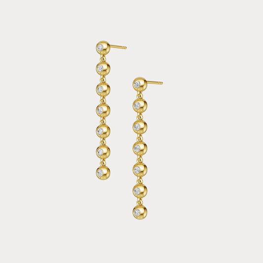 Gold earrings with embedded diamonds on a light gray background