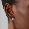 Gold earring worn by a person with a neutral background