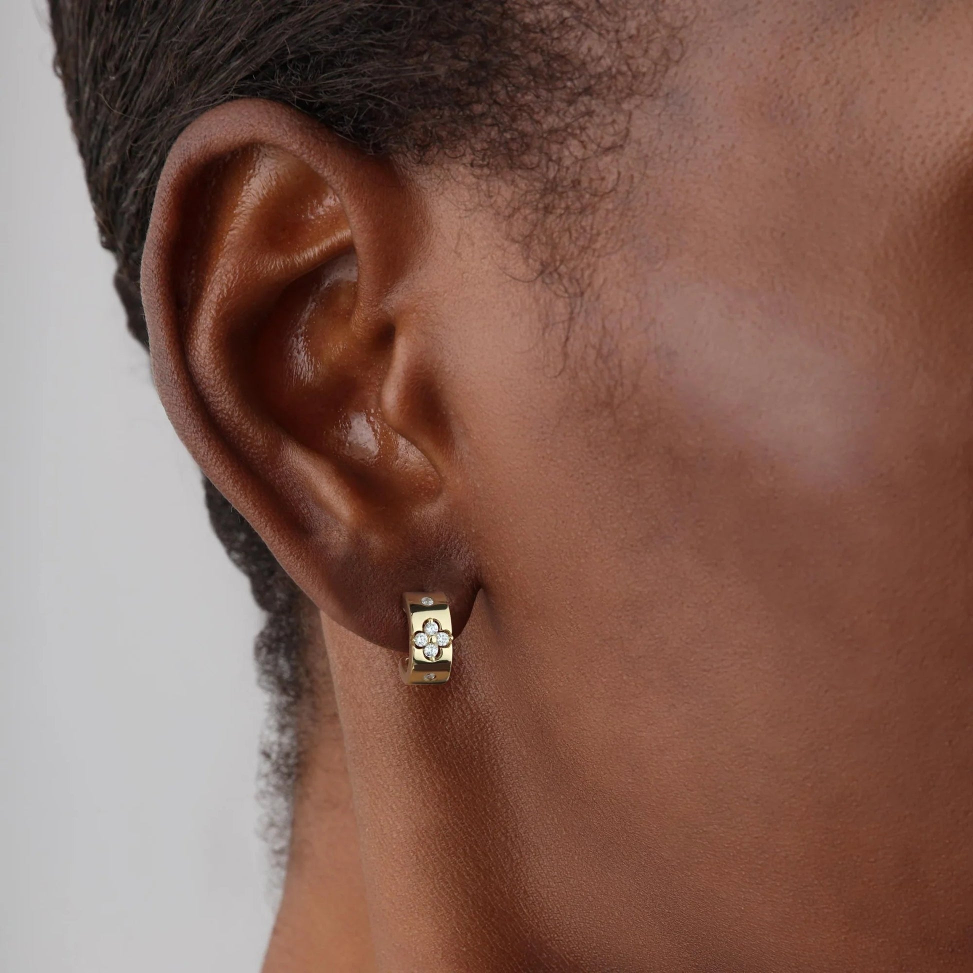Gold earring worn by a person with a neutral background