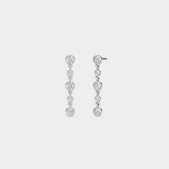 Pair of silver drop earrings with clear gemstones on a light gray background