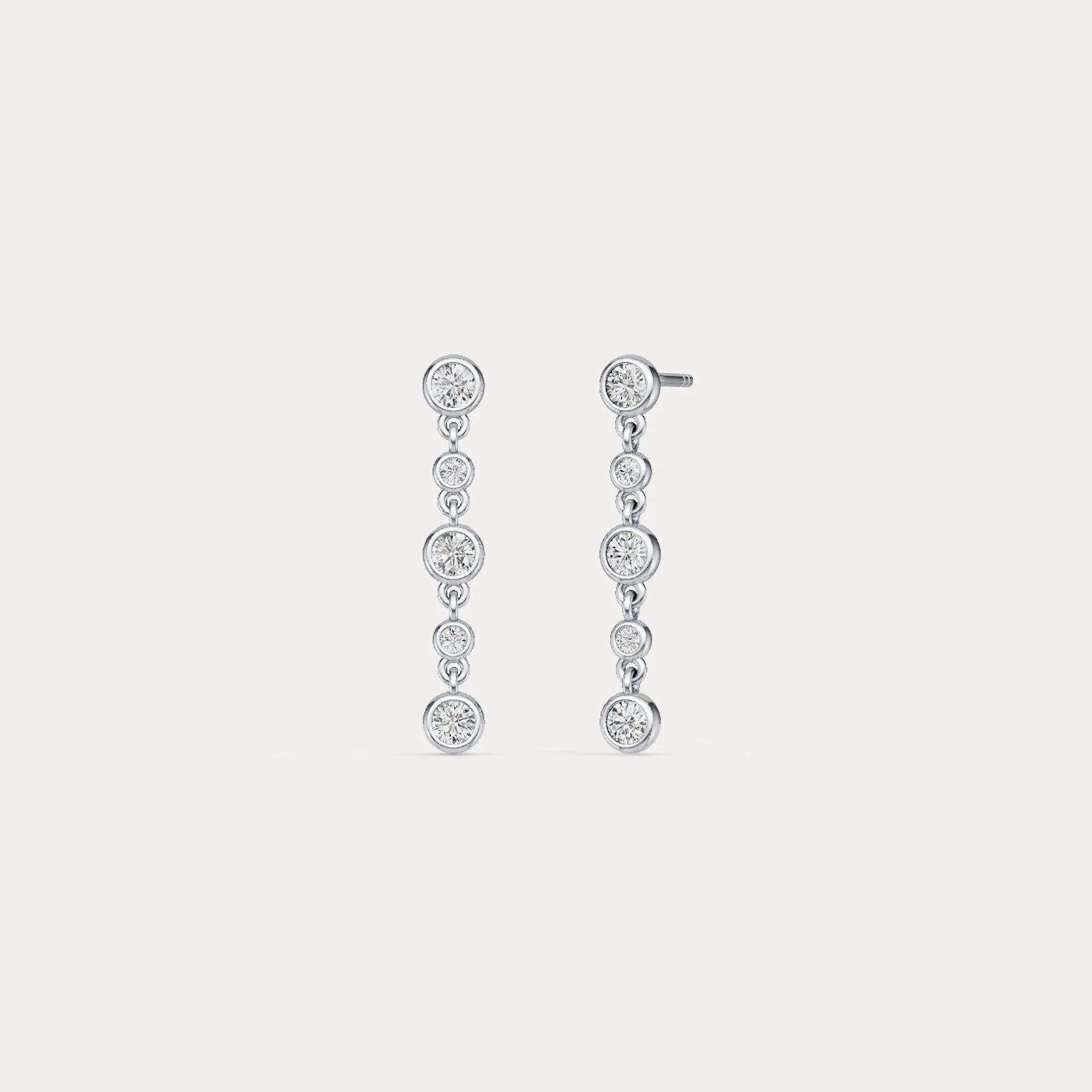Pair of silver drop earrings with clear gemstones on a light gray background