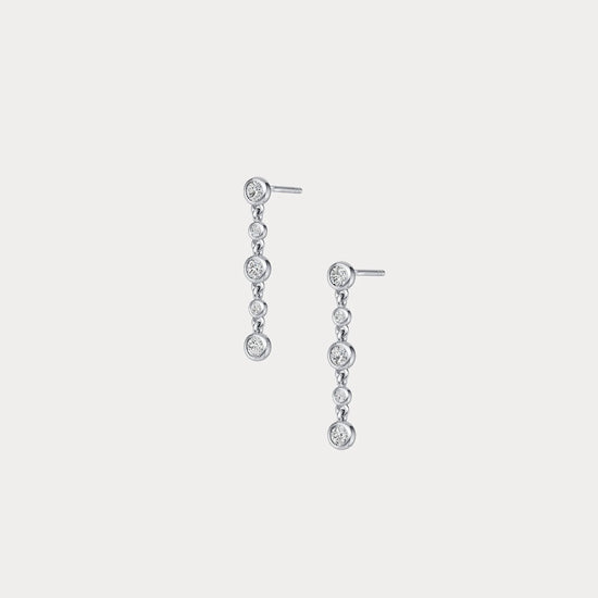 Pair of silver earrings with clear stones on a light gray background