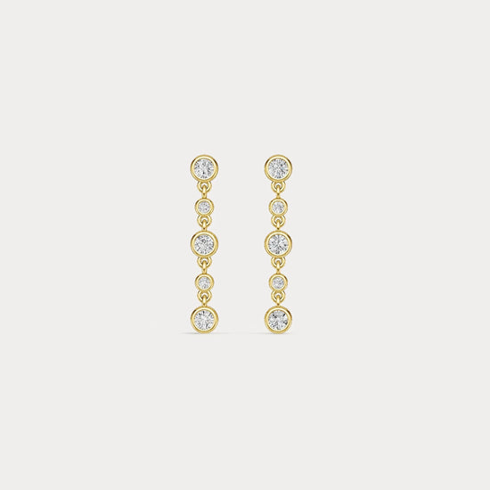 Gold earrings with clear stones on a light gray background