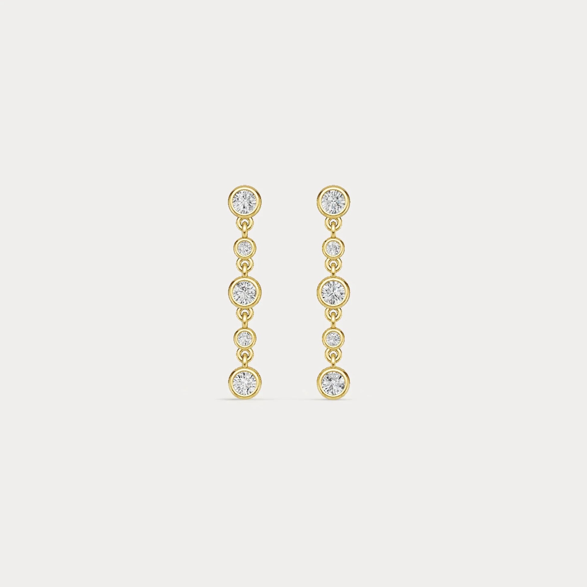 Gold earrings with clear stones on a light gray background