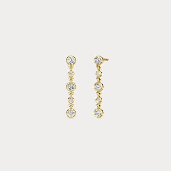 Gold earrings with clear stones on a light gray background