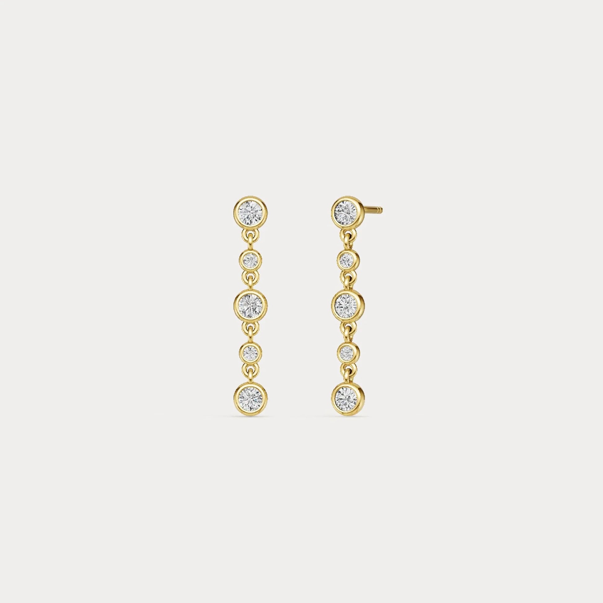 Gold earrings with clear stones on a light gray background