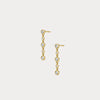 Gold earrings with clear stones on a light gray background