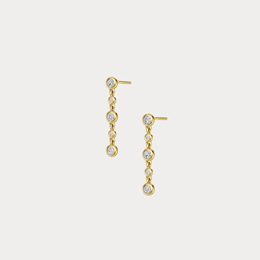 Gold earrings with clear stones on a light gray background