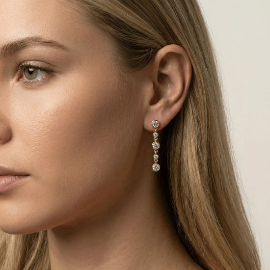 Close-up of a woman wearing a gold earring with multiple small diamonds.