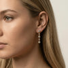 Close-up of a woman wearing a gold earring with multiple small diamonds.