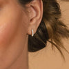 Close-up of an ear wearing a diamond earring with a blurred background