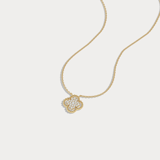 Gold necklace with a heart-shaped pendant on a light gray background