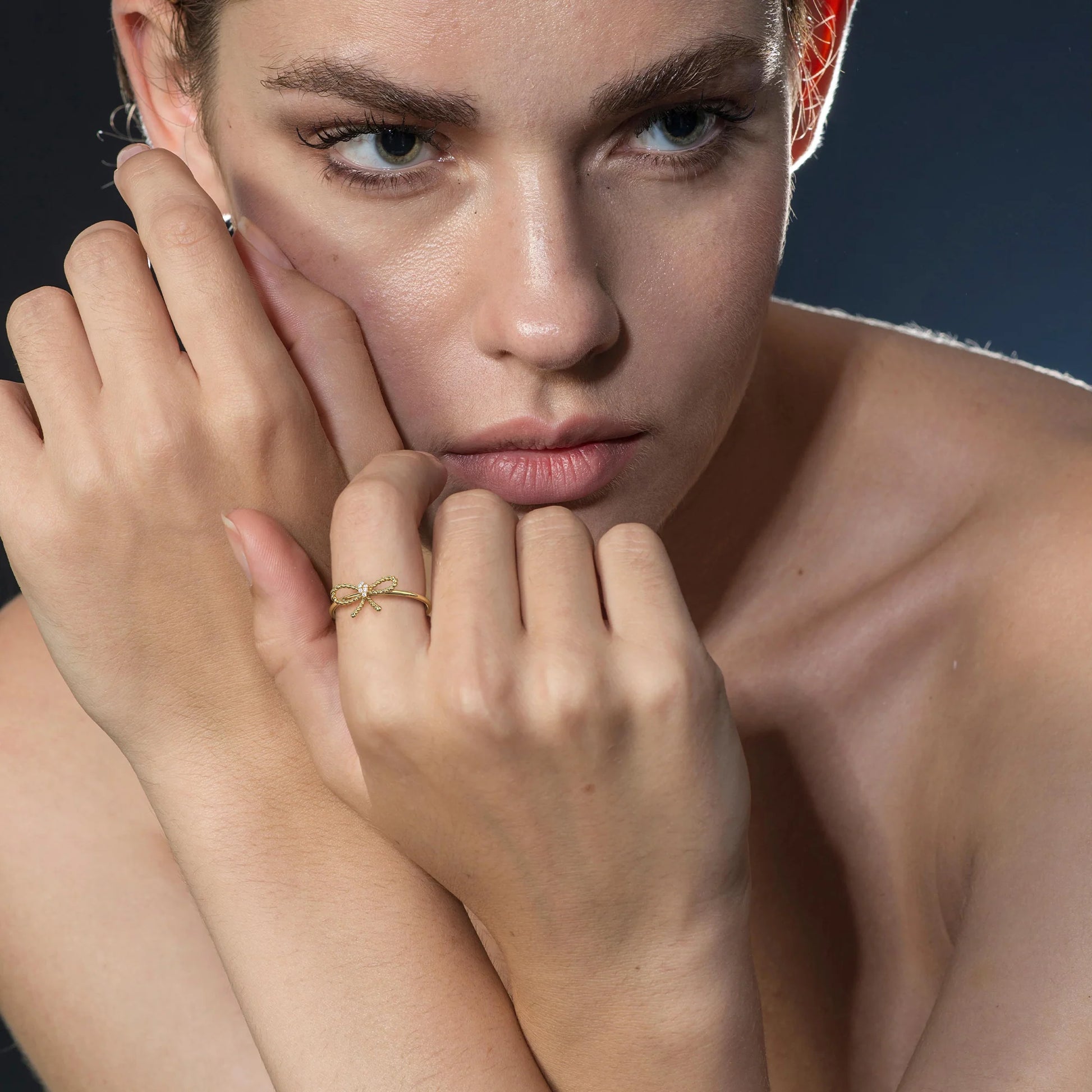 Woman wearing a gold ring with a blue background