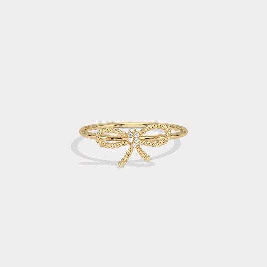 Gold bow-shaped ring on a light beige background