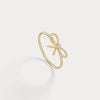 Gold bow-shaped ring on a light gray background