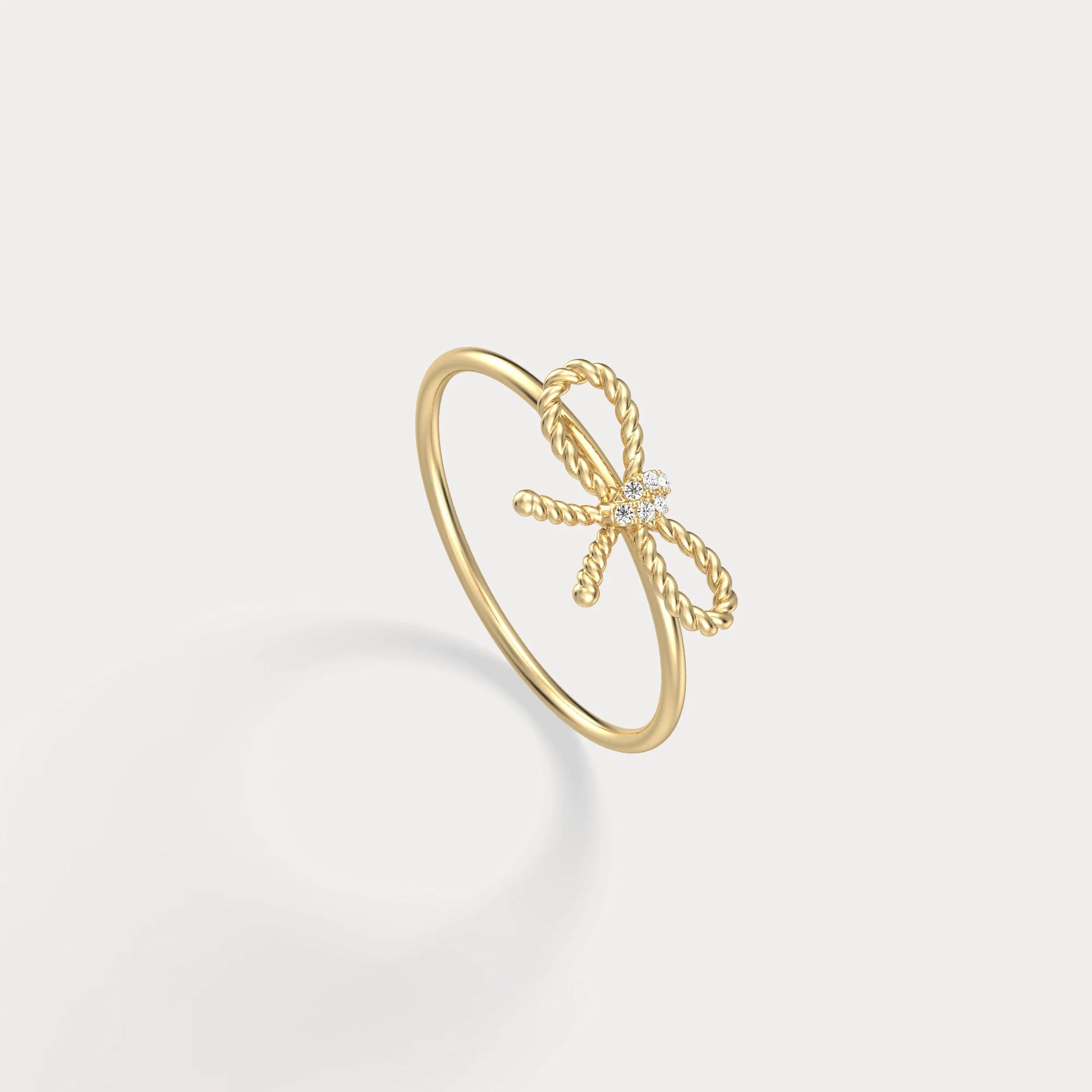 Gold bow-shaped ring on a light gray background