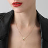 Gold necklace with a pendant worn by a model against a neutral background