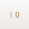 Gold hoop earrings with embedded stones on a light beige background
