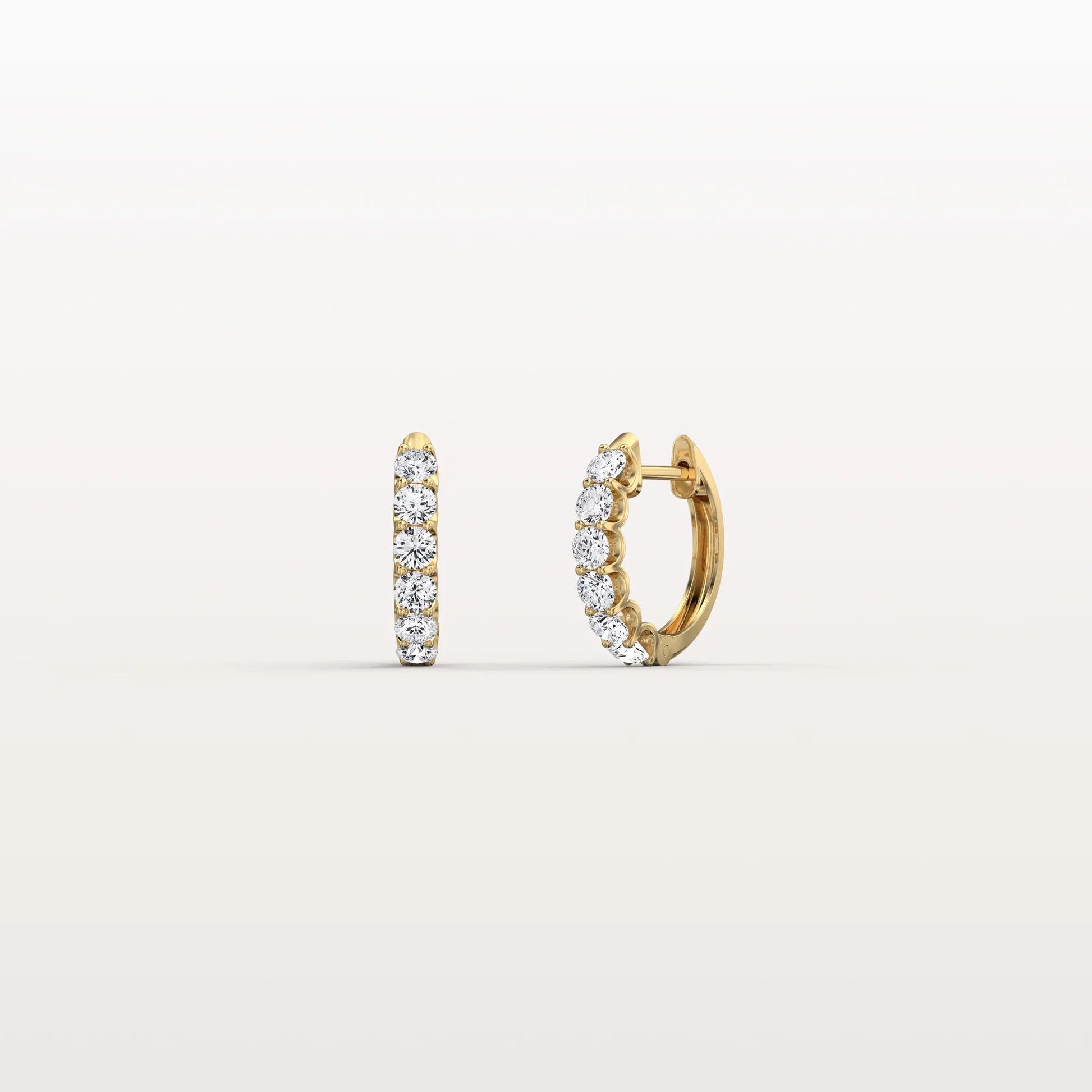 Gold hoop earrings with embedded stones on a light beige background