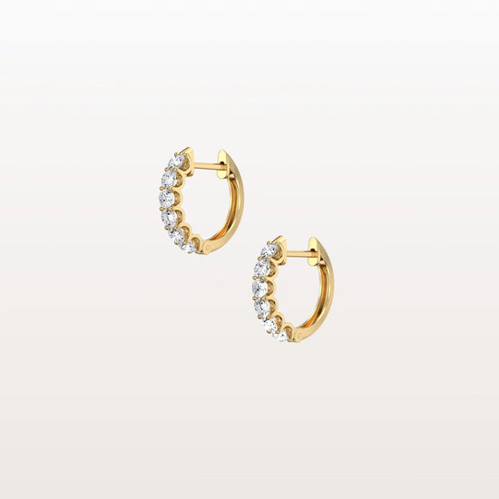 Gold hoop earrings with clear gemstones on a light beige background