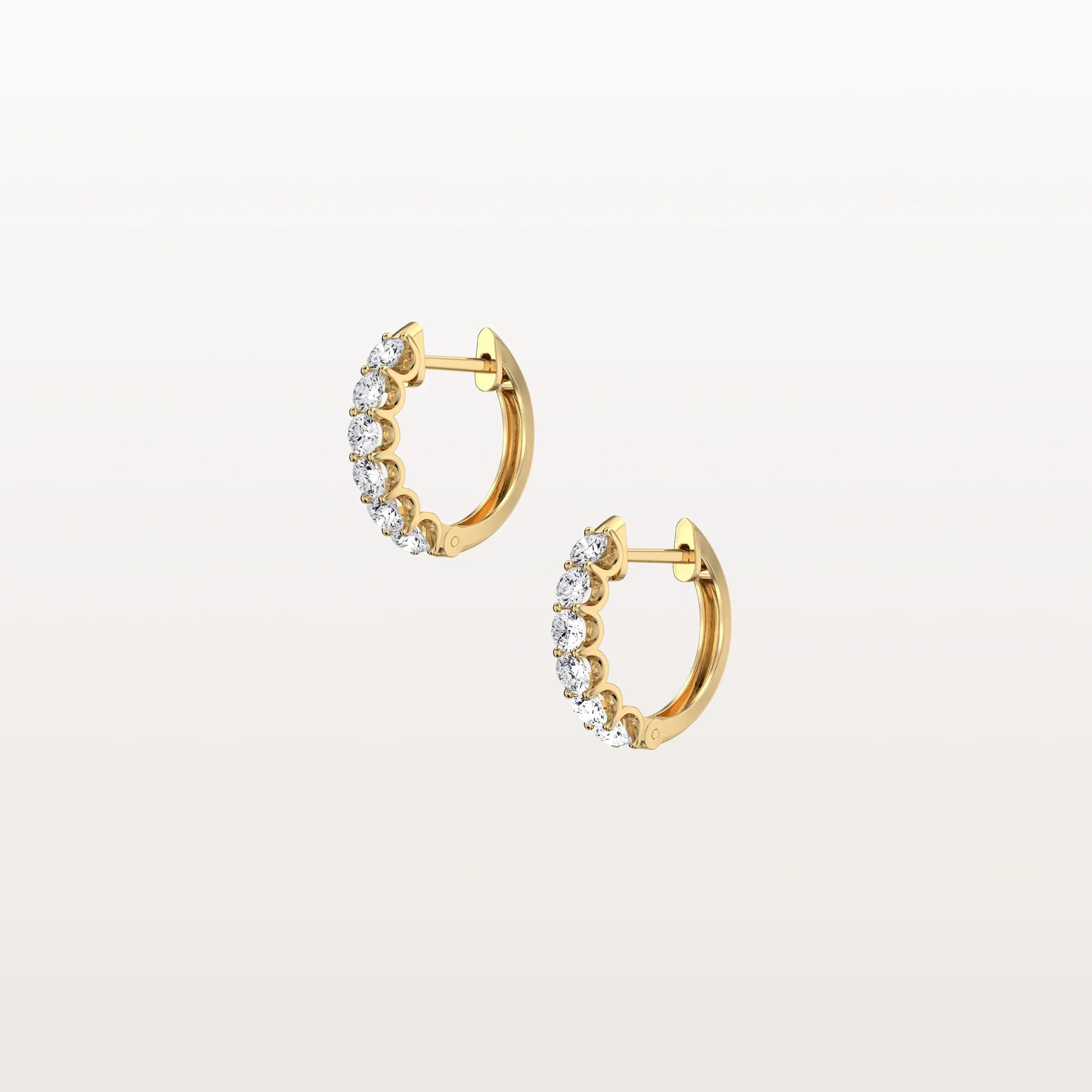 Gold hoop earrings with clear gemstones on a light beige background