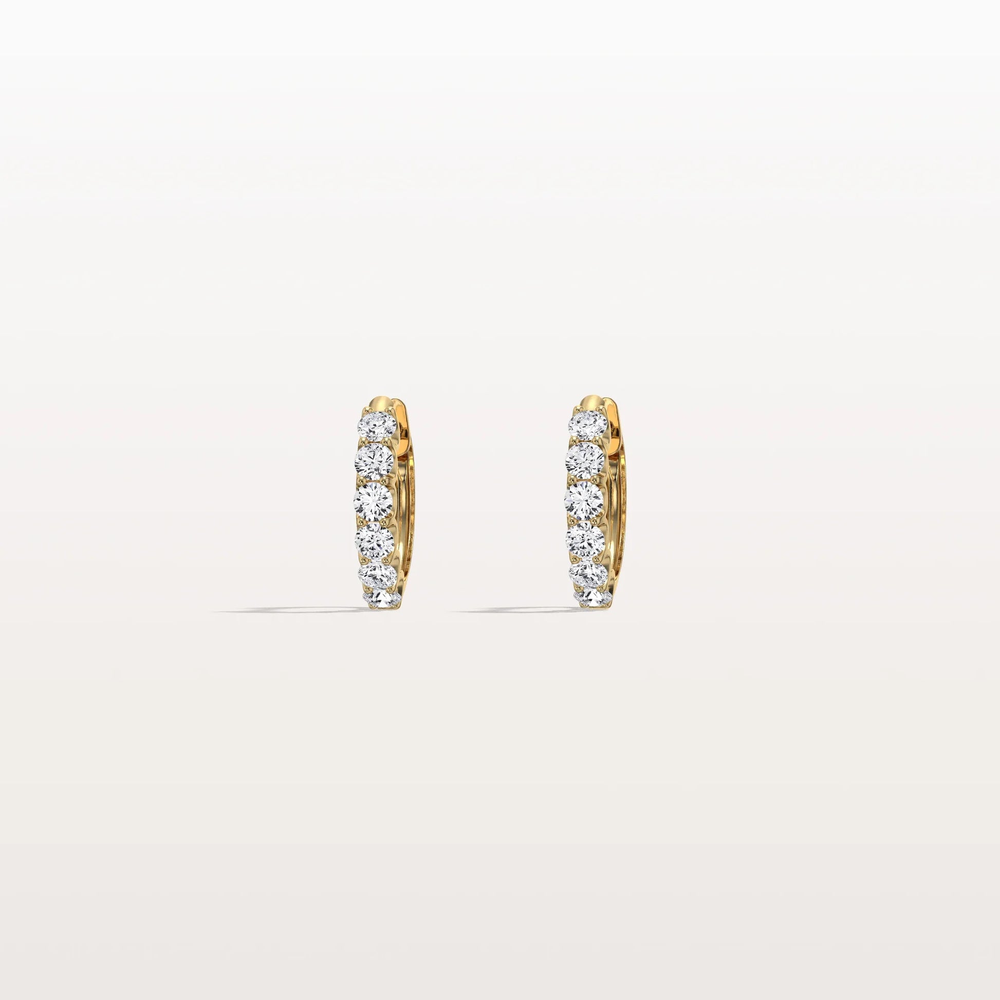 Gold hoop earrings with embedded diamonds on a light beige background