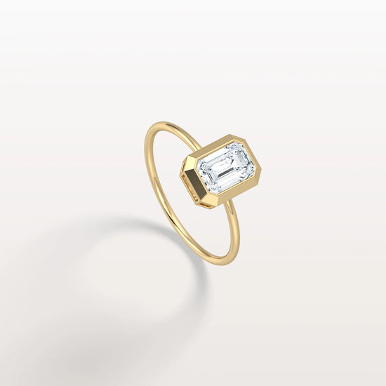 Gold ring with a rectangular diamond on a light gray background