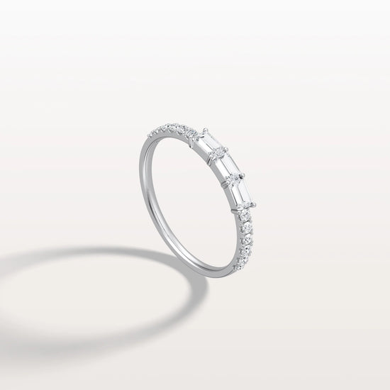 Diamond ring with baguette and round cut diamonds on a light gray background