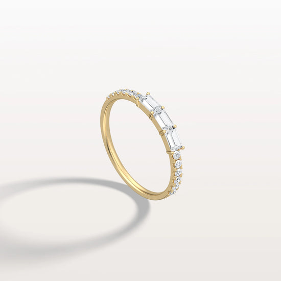 Gold ring with baguette diamonds on a light gray background