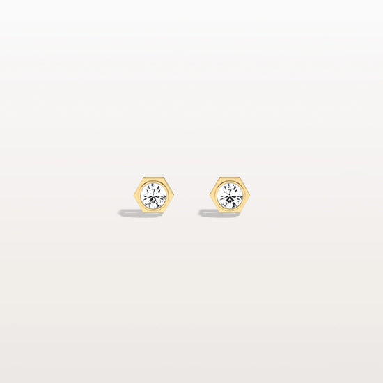 Gold hexagonal earrings with clear gemstones on a light gray background