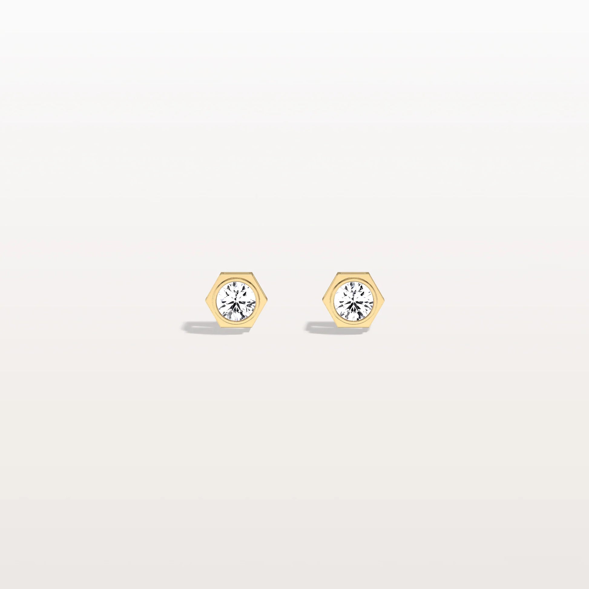 Gold hexagonal earrings with clear gemstones on a light gray background