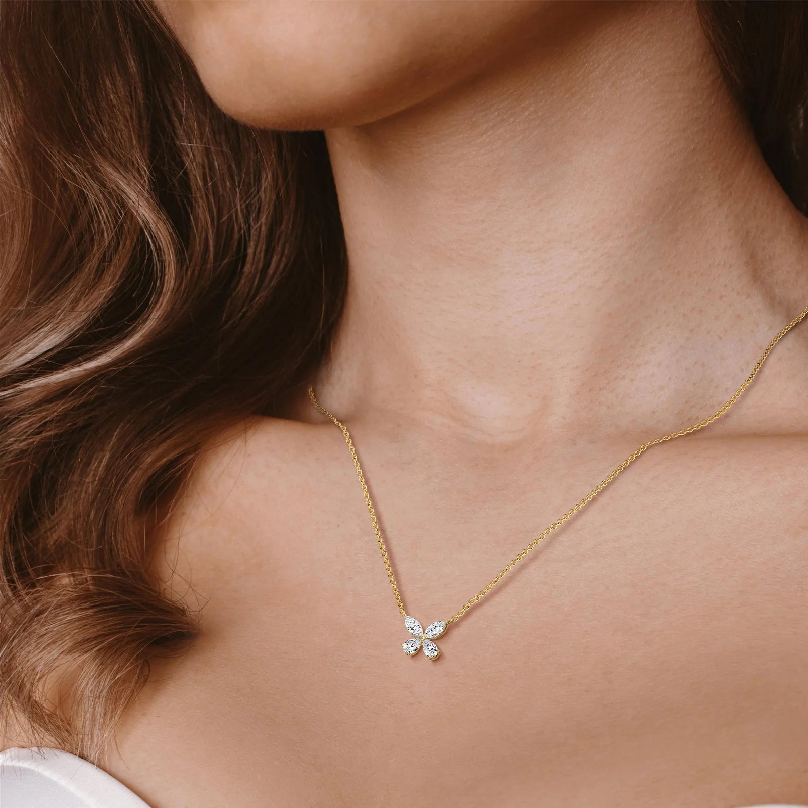 Close-up of a person wearing a butterfly gold necklace with a diamond pendant.